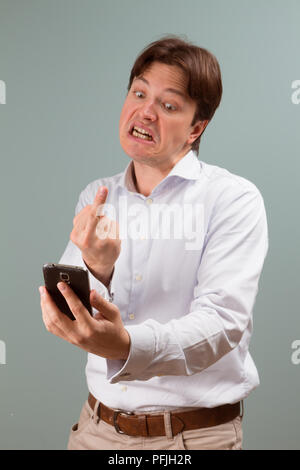 Handsome angry businessman showing broken smartphone with crashed screen. Isolated on white background. Stock Photo