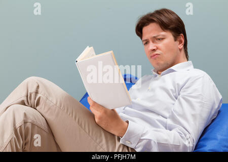 Man reads a book with confused face expression Stock Photo