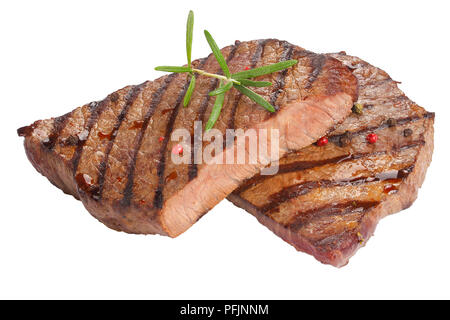 hot delicious medium well grilled juicy beef steaks decorated with rosemary and peppercorn isolated on white background, view from above, close-up Stock Photo