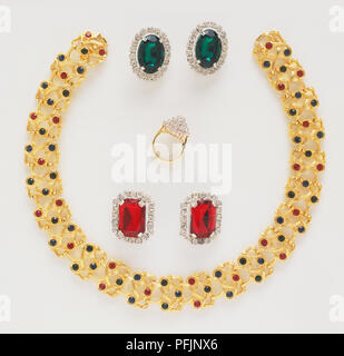 Gold necklace with red and green jewels, diamond ring and pairs of ruby-red and green gemstone earrings Stock Photo
