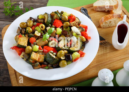 close-up of hot Italian stew with vegetables, green olives, capers, celery and herbs on a white plate view from above Stock Photo