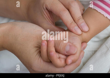 Woman taking baby girl's pulse, close-up Stock Photo