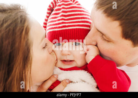 Parents kissing baby in cheeks Stock Photo