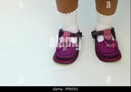 Toddler with pair of purple shoes on wrong feet, close-up Stock Photo