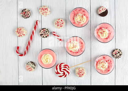 delicious Christmas or New Year dessert -  Cheese Mousse topped with whipped cream rose in glass cups on wooden board, with candy walking sticks and c Stock Photo