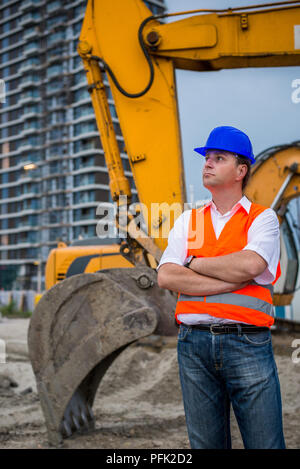 Engineer in front of excavator on a construction site Stock Photo