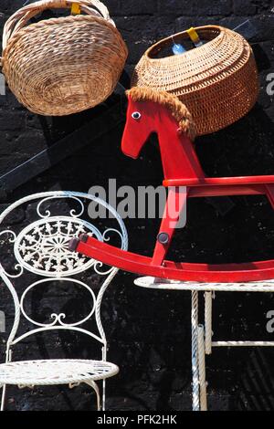 Great Britain, England, woven baskets, wrought iron chair and rocking horse on antiques stall Stock Photo