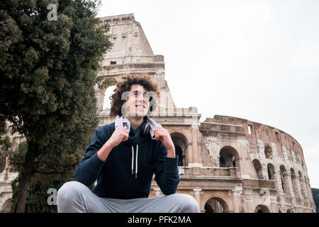 Handsome young sportsman relaxing after training with a towel around his neck in front of Colosseum in Rome Stock Photo