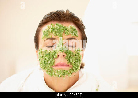Woman in towelling robe, eyes shut, wearing face mask, head and shoulders Stock Photo