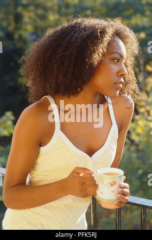 Woman on balcony holding cup of tea Stock Photo