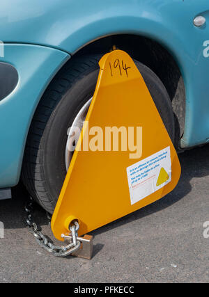 An untaxed car with a wheel clamp on the wheel Stock Photo