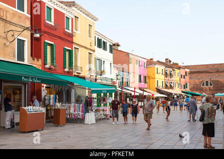 Sunset in the colourful fishing village on Burano Island, Venice, Veneto, Italy. Via Baldassare Galuppi, the main street, with shops, tourists and res Stock Photo