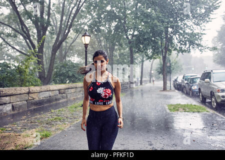 Hispanic Woman Running in the Rain Stock Photo