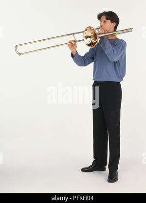 Young man playing trombone, side view Stock Photo