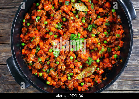 delicious classic ragu with minced beef, vegetables, green peas and tomatoes in black casserole - ingredient for pasta bolognese or shepherd's pie, vi Stock Photo