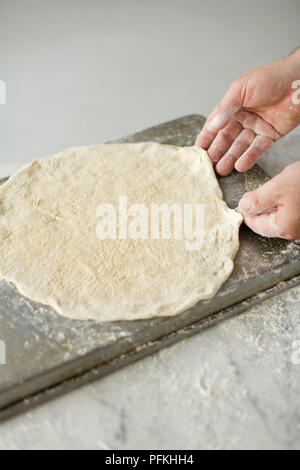 Hands stretching pizza dough into shape, close-up Stock Photo
