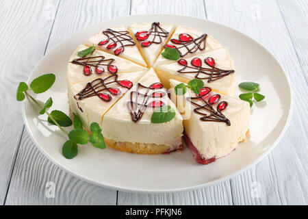 close-up of delicious ornately decorated with chocolate and jelly cheesecake with bottom layer consists of sponge cake with berry sauce, on white plat Stock Photo