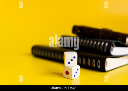black and blue notebooks on a yellow background with white dice to calculate the bet Stock Photo