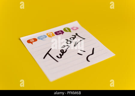 inscription in black marker Tuesday on white sticker yellow background Stock Photo