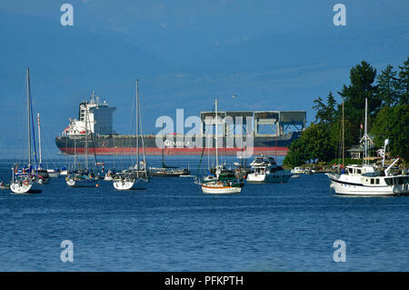 Sail boats , motor boats and a sea going container ship moored in the harbour at Nanaimo on Vancouver Island British Columbia Canada. Stock Photo