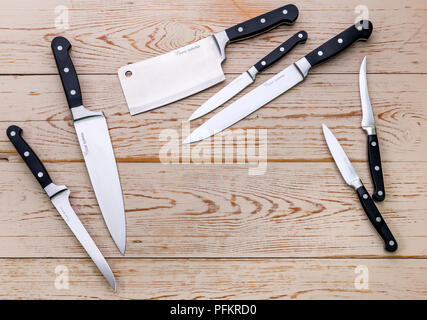 An assortment of various kitchen knives on a wooden background. Stock Photo