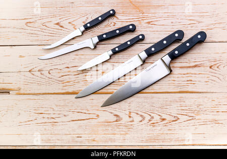 An assortment of various kitchen knives on a wooden background. Stock Photo