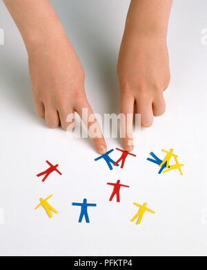 Girl's fingers pointing to pair of cut-out paper figures Stock Photo