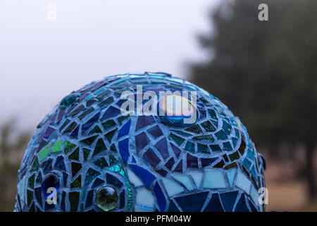 Close up of mosaic garden ball in shades of blue in swirl pattern made from stained glass tiles, abstract design Stock Photo