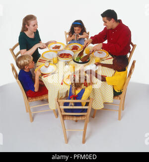 Two adults and four children eating at a table, high angle view Stock Photo