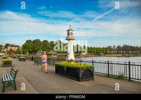 Person jogging past the Scott Memorial in Roath Park Lake in the suburbs of Cardiff, wales. Stock Photo