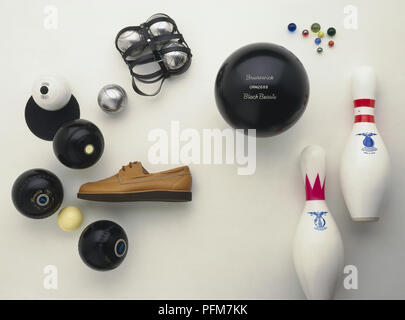 Bowling sports equipment, including crown-green bowls and jack, flat-green bowls and jack, bowling shoes, four silver boule balls, ten-pin bowling ball and pins, colourful marbles Stock Photo