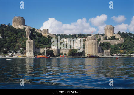 Asia, Turkey, view of the Fortress of Europe situated at the narrowest point of the River Bosphorus, built by Mehmet the Conqueror in 1452 to enable him to capture Constantinople, watch towers, Turkish flag flying, boats on water beneath. Stock Photo