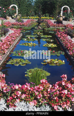 Canada, Vancouver Island, Butchart Gardens, lily pond surrounded by pink and white flowers, high angle view. Stock Photo