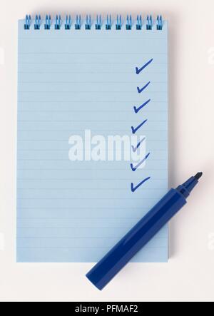 Ticks on blue notepad, blue marker pen nearby, close-up Stock Photo