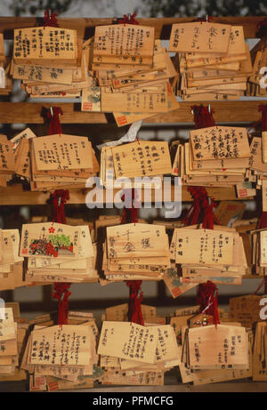 Japan, Ema boards, small wooden plaques inscribed with wishes and prayers, on display at Shinto shrine, close up. Stock Photo