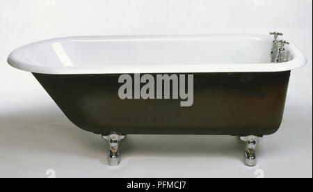 Early 20th-century cast-iron roll-top bath, black and white with metal feet, side view. Stock Photo
