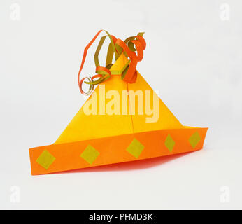 Yellow and orange paper hat with streamers on top Stock Photo