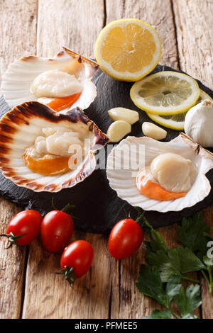 Fresh scallops in a shell with vegetable ingredients close-up on a table. vertical Stock Photo