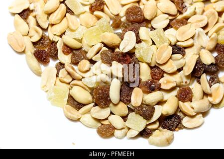 On a white isolated background lies a mixture of nuts and fruits. The mixture consists of peanuts, candied fruits, raisins and dried bananas. Stock Photo