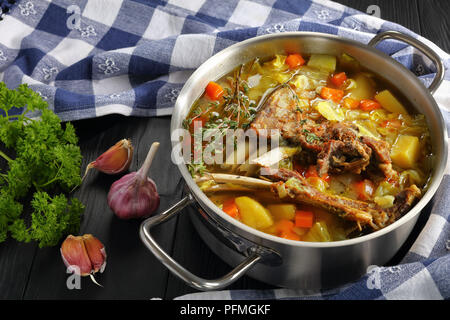 close-up of delicious Icelandic Lamb winter hot Soup with vegetables and spices or kjotsupa in a stainless steel casserole pan on wooden table with ki Stock Photo