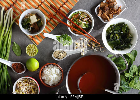traditional japanese miso soup in a bowl. ingredients on concrete table - tofu, miso paste, wakame seaweeds, steamed rice, shiitake mushrooms, sprouts Stock Photo