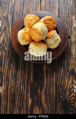 delicious freshly baked homemade english scones on clay plate on wooden table,  vertical view from above Stock Photo
