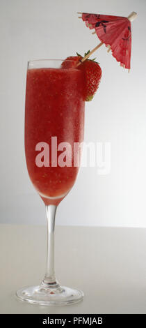 Glass of strawberry daiquiri cocktail decorated with umbrella and fresh strawberry, close up. Stock Photo