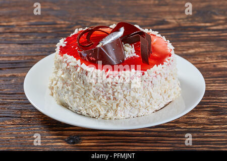 delicious festive torte ornately decorated with white chocolate flakes, berry jelly and chocolate chips, view from above, close-up Stock Photo