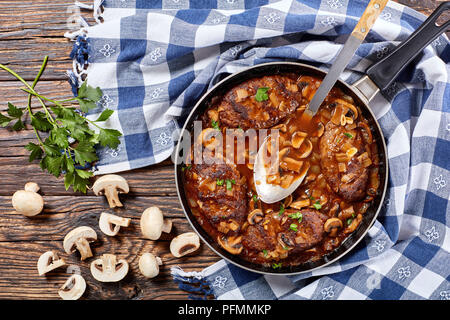 hot savory juicy salisbury beef steaks with delicious mushroom onion gravy in a skillet with sauce spoon, view from above Stock Photo