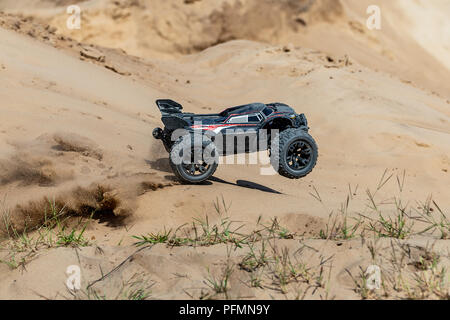 Big radio controlled buggy car driving fast and slipping on sand. RC toy moving fast on cross-terrain surface with dust and mud outdoors. Children hobby concept Stock Photo