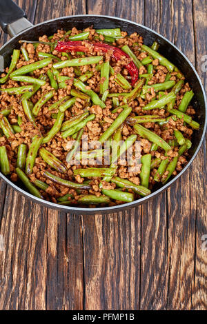 Pork Stir Fry with Green Beans in a skillet, vertical view from above Stock Photo