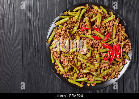 Szechuan Pork Stir Fry with charred Green Beans served on a plate on a wooden table, view from above Stock Photo