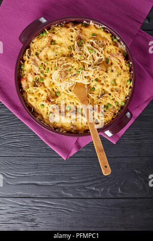 Tetrazzini - pasta, cream sauce, chicken meat, melted cheese, green peas, mushrooms casserole in a baking dish with ingredients at background, classic Stock Photo