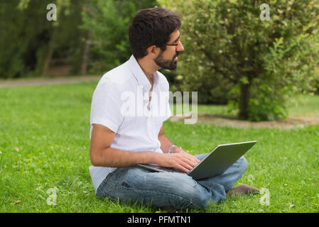 Young hipster man working in the park Stock Photo
